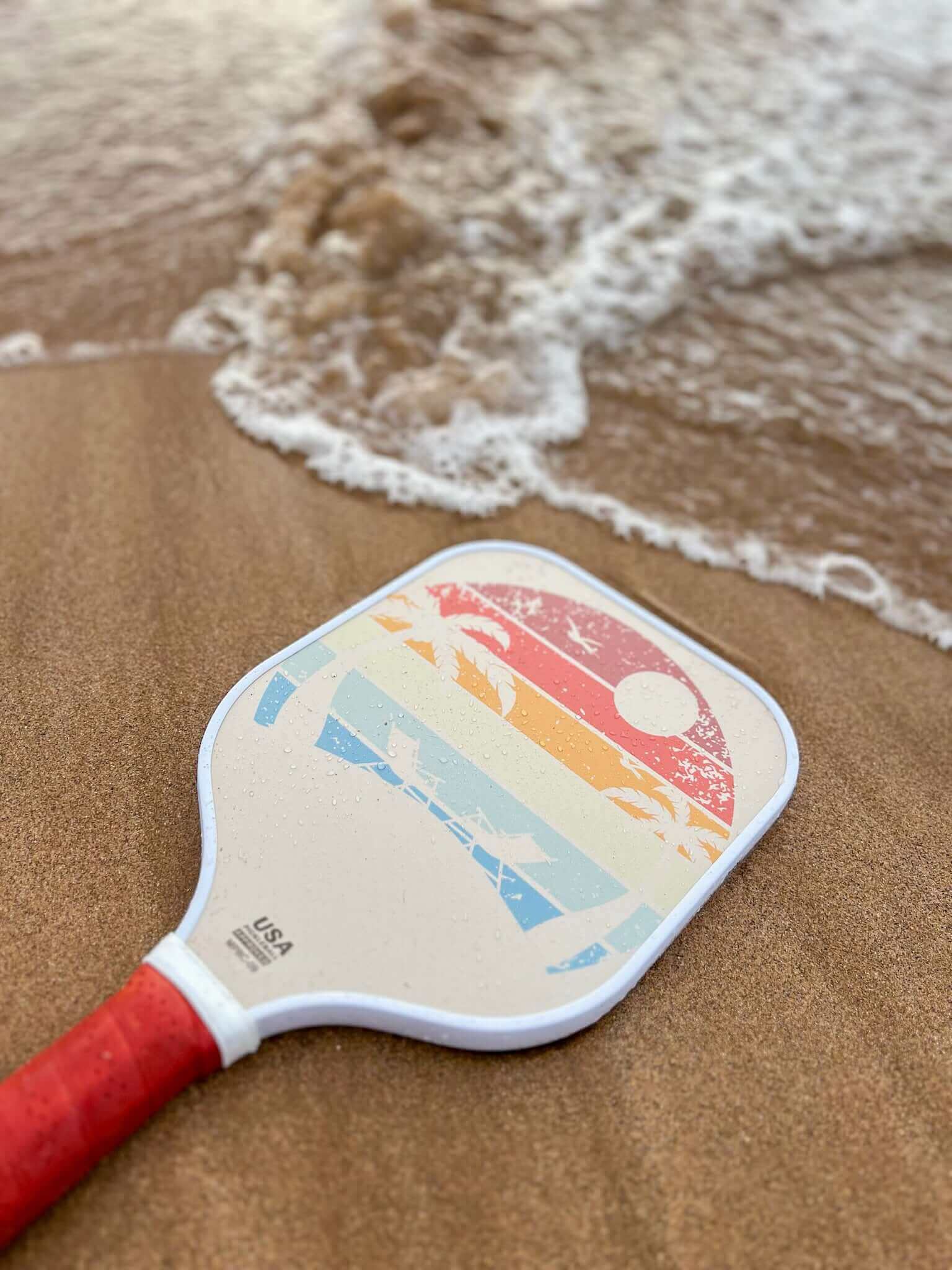 pickleball paddle on the beach with a paddle and pickleball water bottle on the beach and waves