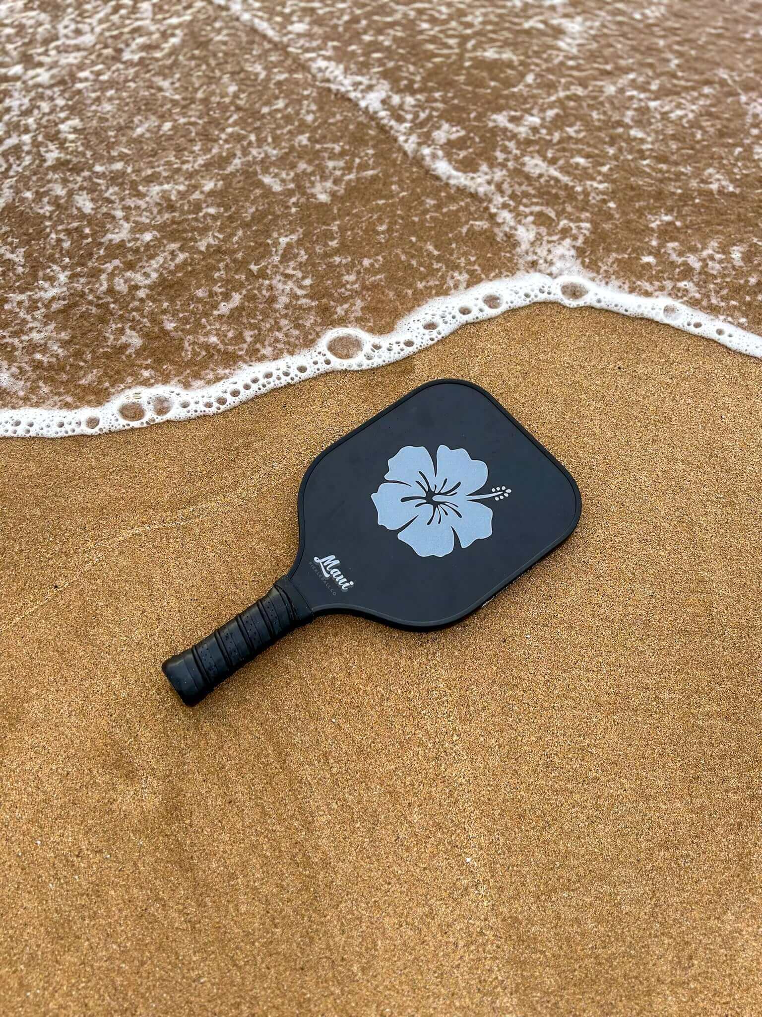 pickleball paddle on the beach with a paddle and pickleball water bottle