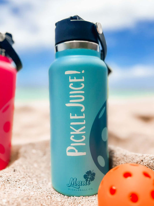 aqua stainless steel water bottle on the beach with a pickleball paddle 