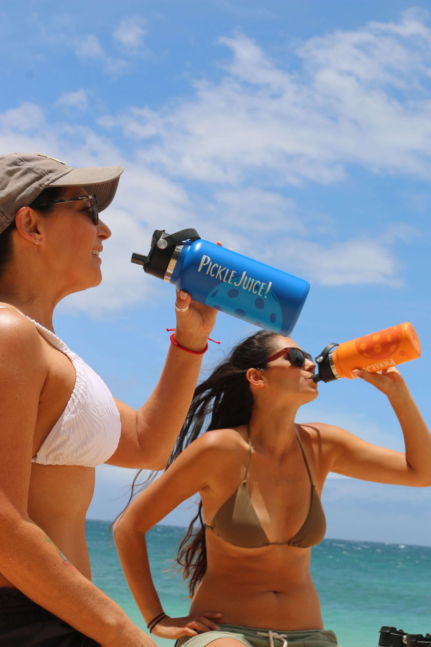 women on the beach drinking from pickleball water bottles